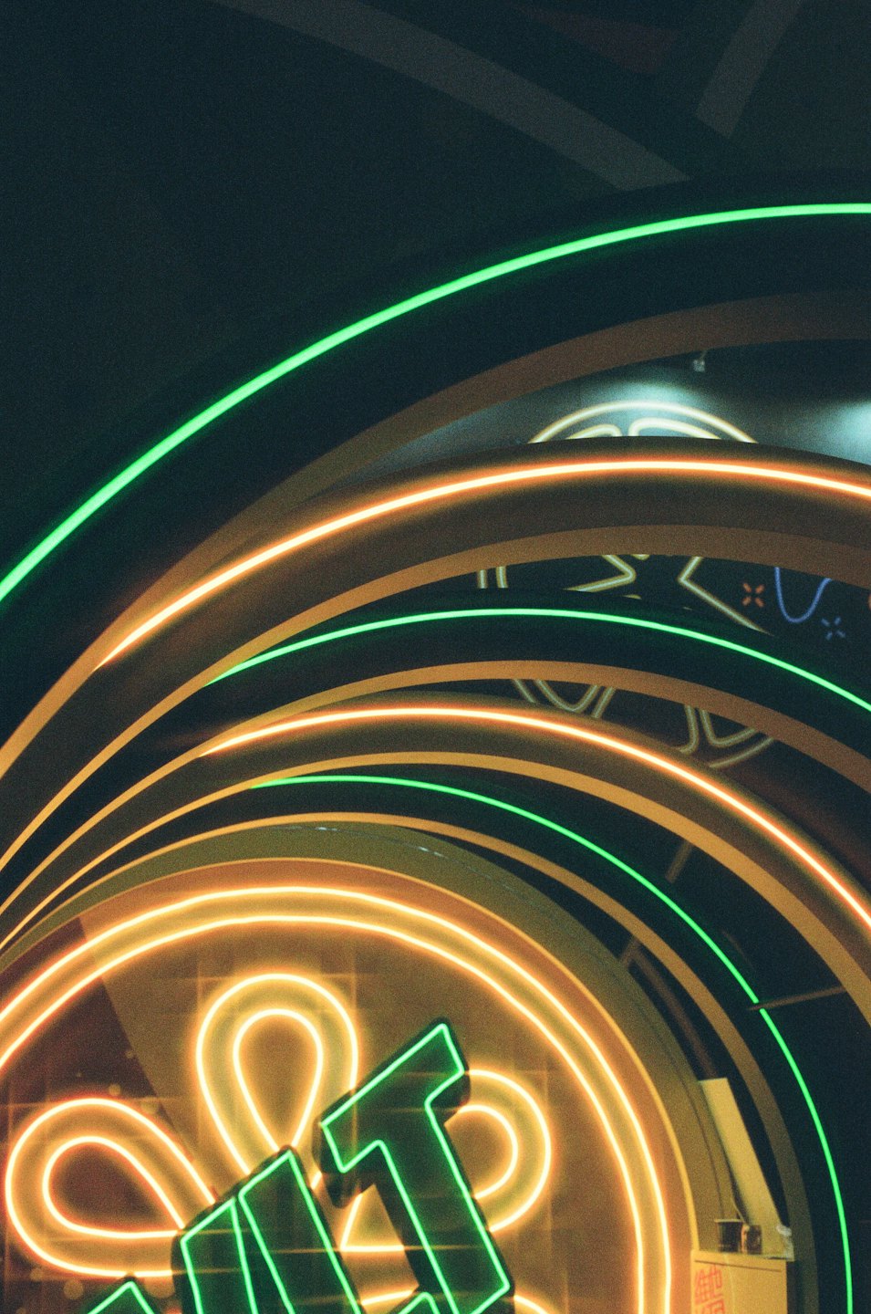 Curved green and orange neon light tubes with visible characters.