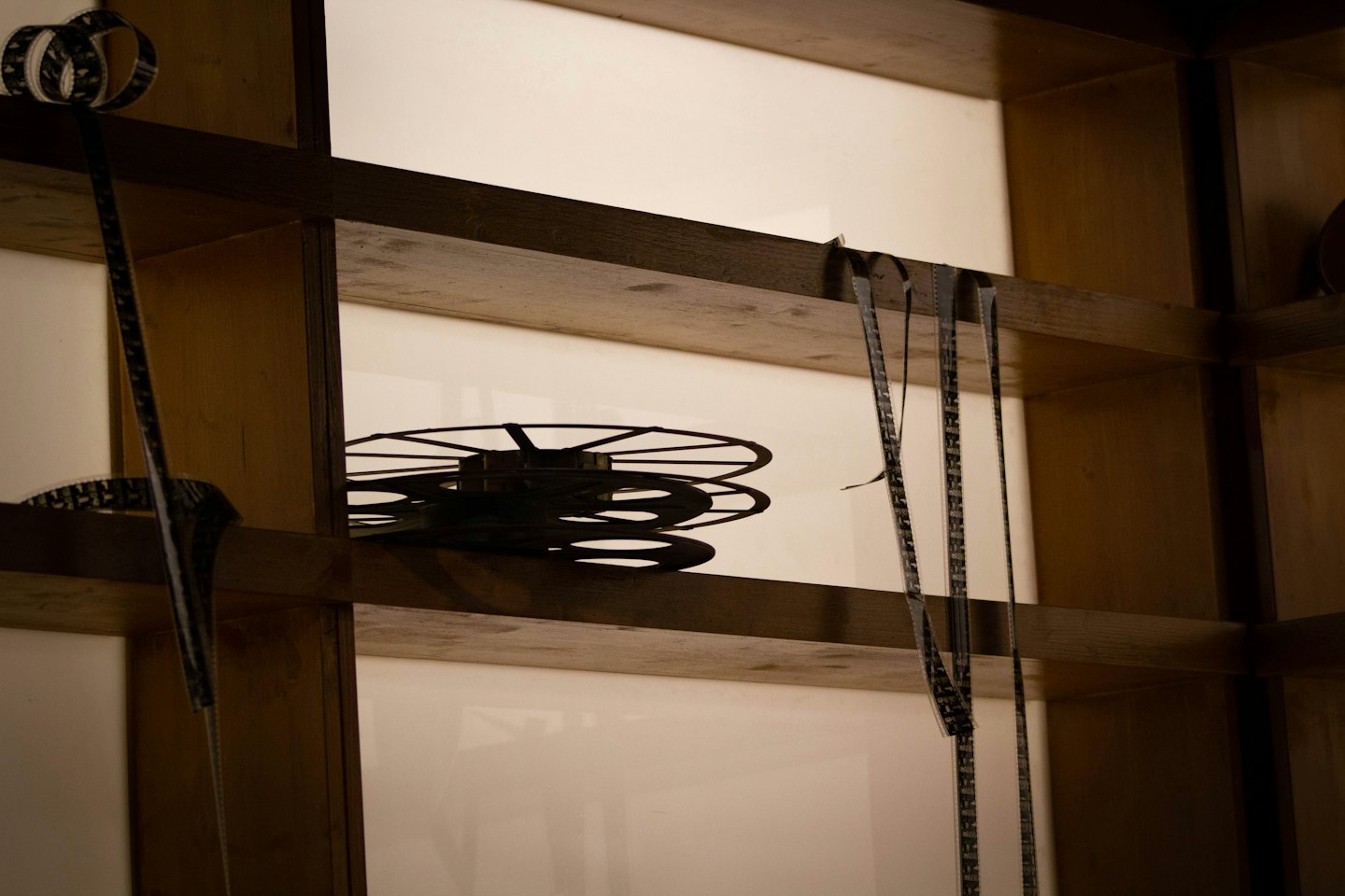 Black film reels stacked on wooden shelves with film strips hanging.