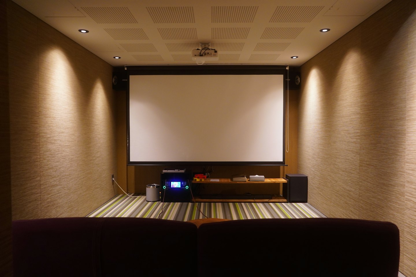 Home theater room with a projection screen and control panel.